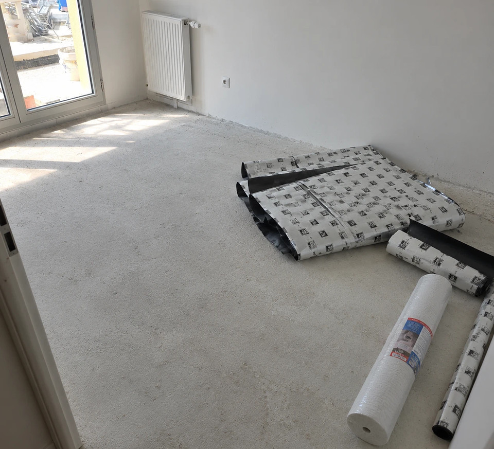 Avant&nbsp;: chambre au support brut, rouleaux de sous-couche en attente de pose